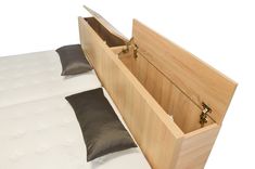 a bed with a wooden headboard and storage compartment on it's bottom side