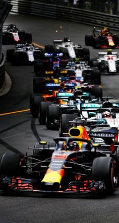 a group of racing cars driving down a street next to each other on a race track