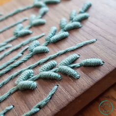 there are many small green plants on the cutting board with string attached to it and threaded together