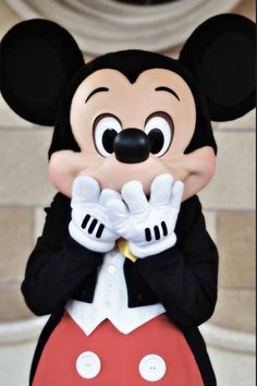 a close up of a person wearing a mickey mouse mask and holding his hands together