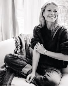 a woman sitting on top of a couch next to a window