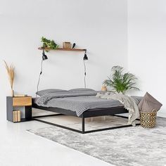 a bed sitting on top of a white floor next to a plant