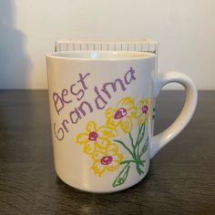 a coffee cup with the words best grandma written on it and flowers painted on it