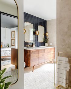 a bathroom with blue tile and gold accents on the vanity, along with a large mirror