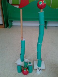 an assortment of toys made out of toilet paper and plastic cups sitting on the floor in front of a green bench