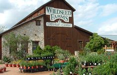 a building with lots of potted plants in front of it and a sign that says wildsee farms