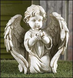 an angel statue sitting in the grass with its hands together and looking at something off to the side