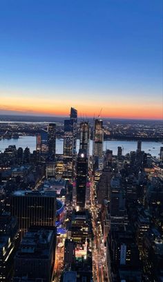 an aerial view of the city at night with lights and skyscrapers in the foreground