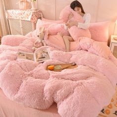 a bed covered in pink fluffy blankets and pillows