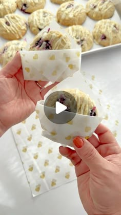 two hands holding pastries with blueberries in them