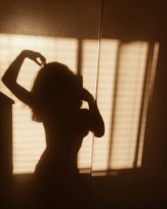 a woman standing in front of a window with her hands on her head and arms behind her back