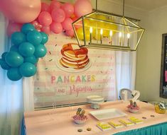 a pancake themed birthday party with pink, blue and yellow balloons hanging from the ceiling