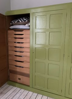 a green cabinet with drawers and pillows on top