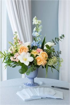 a blue vase filled with lots of flowers on top of a table