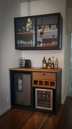 a small bar with liquor bottles on the shelves and an open wine glass cabinet above it