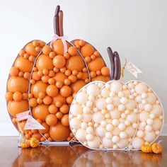 two pumpkins made out of balloons sitting next to each other on a wooden table