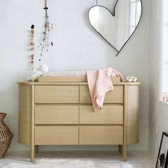 a baby's crib with a heart shaped mirror on the wall above it