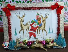 a christmas card with santa claus and reindeers on it, in front of holiday decorations