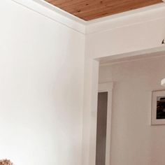 a teddy bear sitting on top of a bed next to a white wall and wooden ceiling