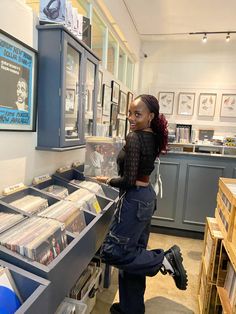 a woman standing in front of a record store counter with records on display behind her