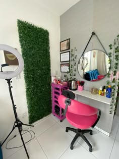 a pink chair sitting in front of a mirror on top of a desk next to a green wall