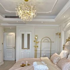 a large white bed sitting in a bedroom next to a chandelier above it