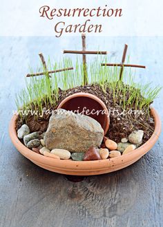 a potted plant with rocks, grass and crosses in it sitting on a table