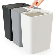 two trash cans one black and the other grey with a finger pointing at it's opening