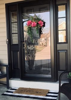 the front door is decorated with pink flowers and black shutters, along with a welcome mat