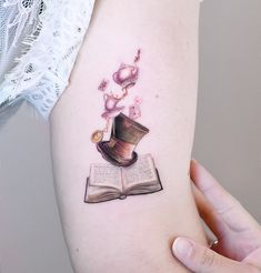 a woman's arm with an open book and hat on it