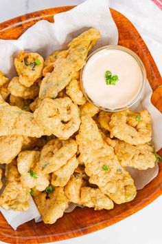 some fried food on a wooden plate with a small bowl of ranch dressing in the background