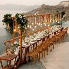 a long table is set up with white flowers and greenery for an outdoor wedding reception