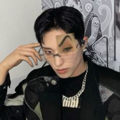 a young man with black hair and glasses has his face cut out to look like an alien