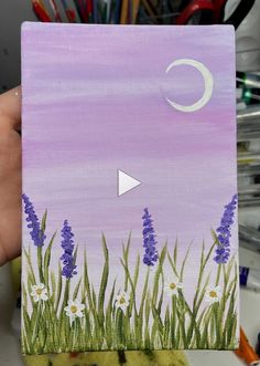 someone is holding up a painting with flowers and the moon in the sky above them