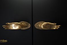 two golden hands are on display in front of a black wall and one is holding the other's hand