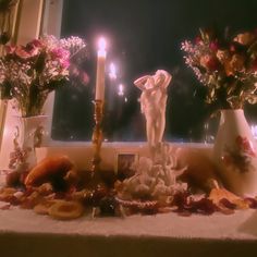 a table topped with vases filled with flowers next to a candle and candlestick