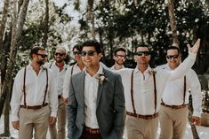 a group of men standing next to each other in front of trees with sunglasses on