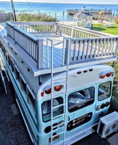 a blue and white bus parked in front of the ocean with a ladder on it's side