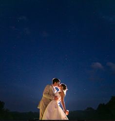 a bride and groom kissing under the night sky