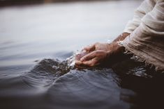 a person is sitting in the water with their hands on his knees