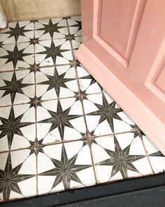 a black and white tiled floor next to a pink door