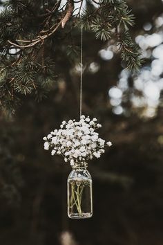 a mason jar filled with baby's breath flowers hanging from a tree