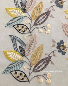 an embroidered design with flowers and leaves on white fabric, showing the details of different colors