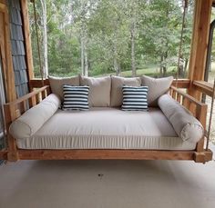 a wooden porch swing with pillows on it