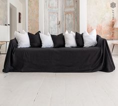 a black couch with white pillows on it in front of a wooden table and wall