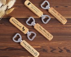 four bottle openers with engraved names on them sitting on a wooden table next to some feathers