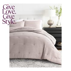 a bed with pink comforter and pillows in front of a night stand on the floor