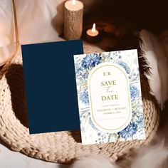 a blue and white save the date card next to a lit candle on a wicker basket