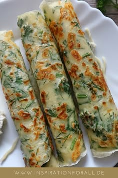 three pieces of food on a white plate with sauces and herbs in the background