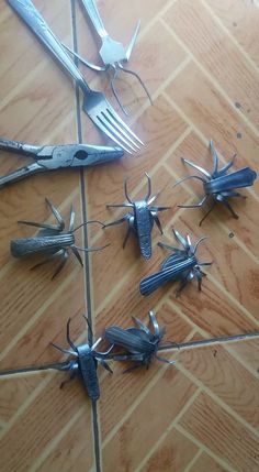 several forks and spoons are laying on the floor with metal bugs attached to them